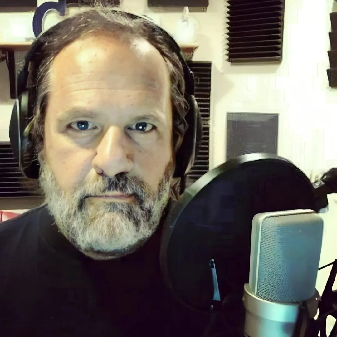 A man with headphones on in front of a microphone.